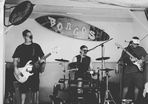 The image shows a black-and-white photo of a band performing at a venue called 