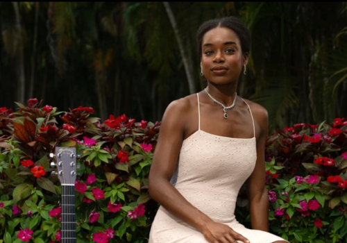 Kimi Tortuga in garden with a guitar.