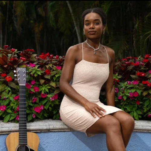 Kimi Tortuga in garden with a guitar.